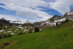 The grassy trail towards Alp Mädens, with snow capped mountains in the background.